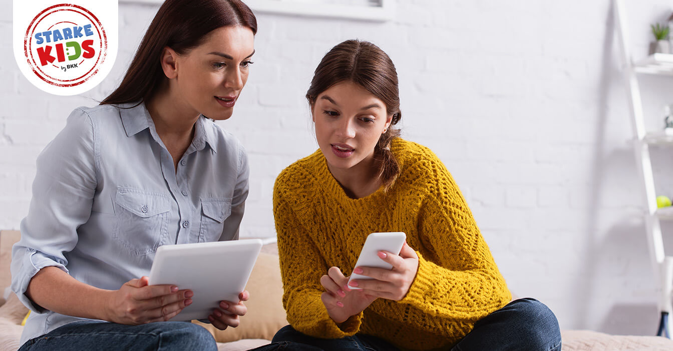 Eine Jugendliche und eine Frau schauen interessiert auf ein Smartphone.